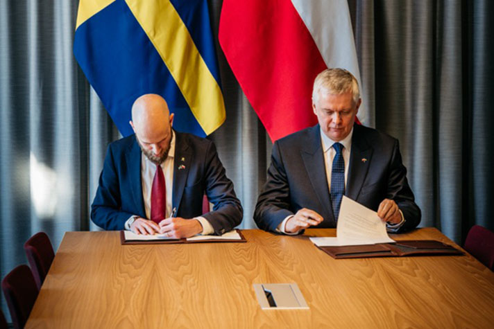 Carl-Oskar Bohlin and Tomasz Siemoniak signing papers.