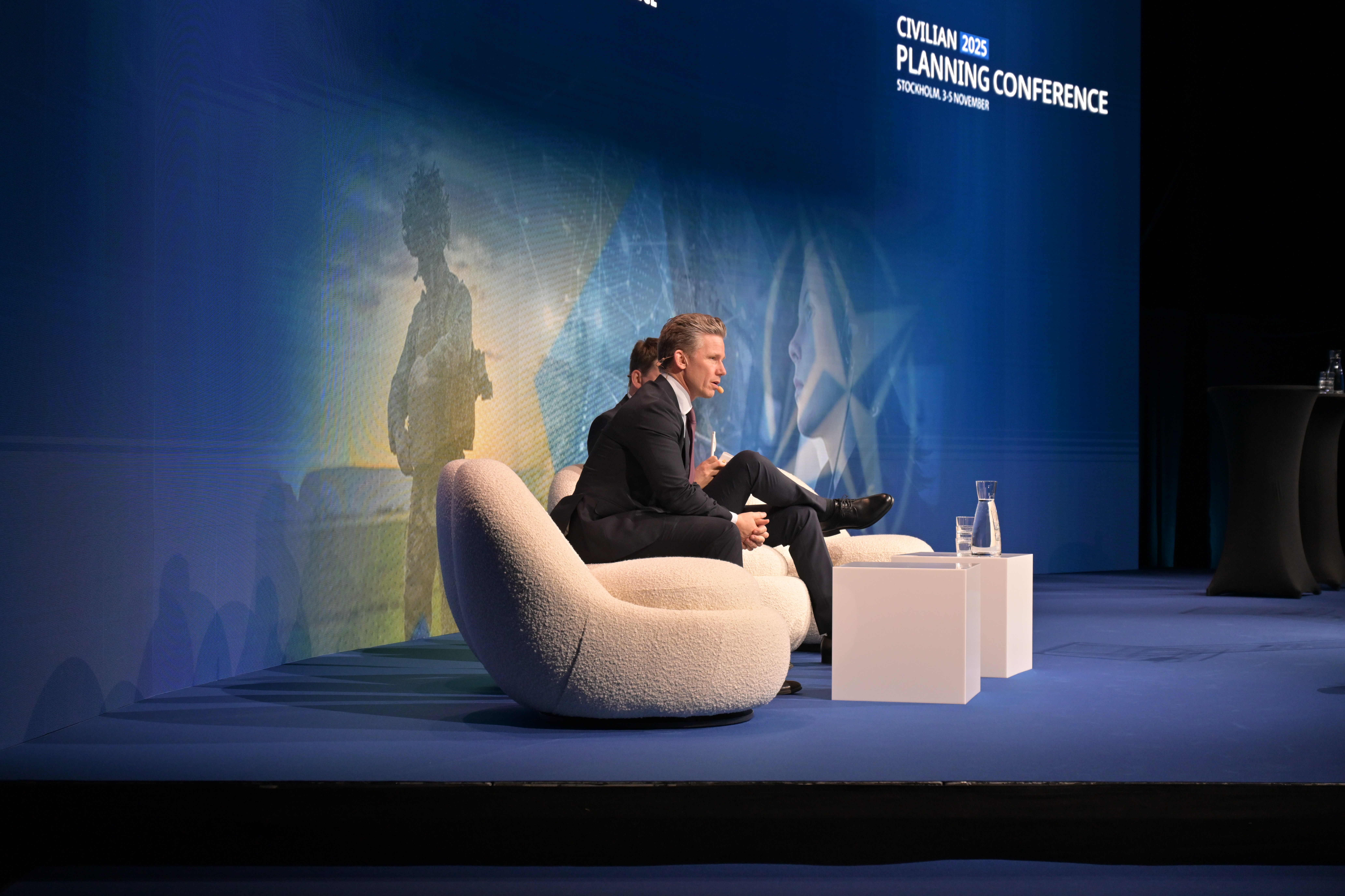 Pål Jonson is sitting in a sofa on a stage.