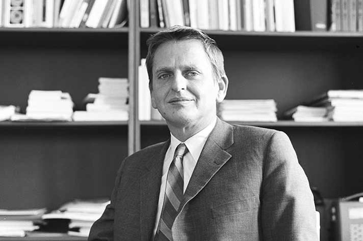 Olof Palme in front of a bookshelf.