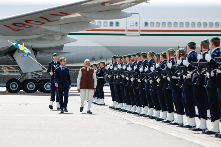Ulf Kristersson and Narendra Modi walk past a guard of honour, with soldiers from the Swedish Armed Forces lined up in formation.