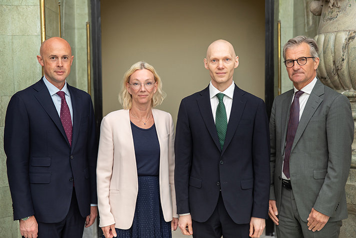 Four people looking in to the camera, standing next to each other. Formal wear.