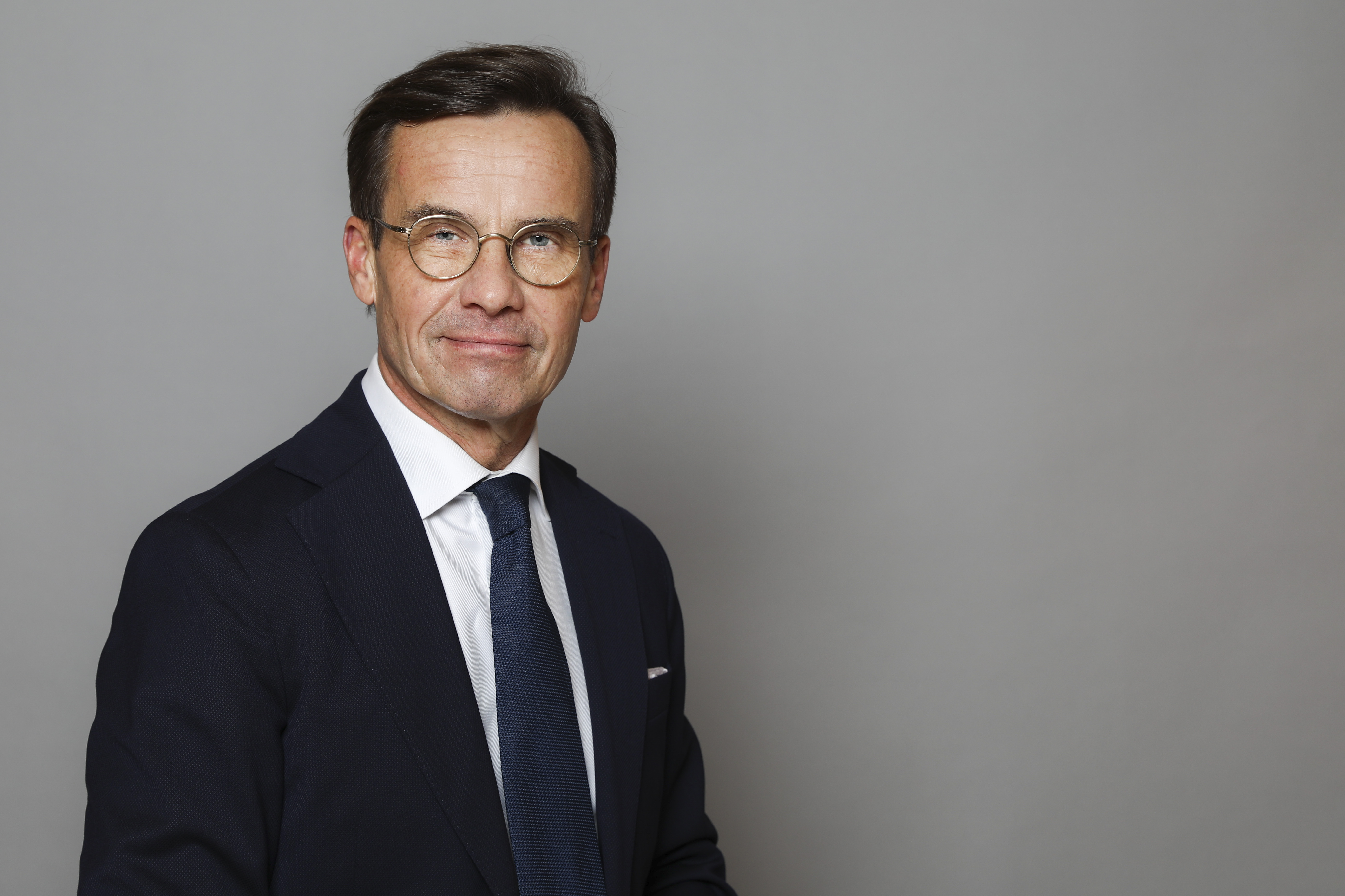 Half-length portrait of Ulf Kristersson against a grey background.