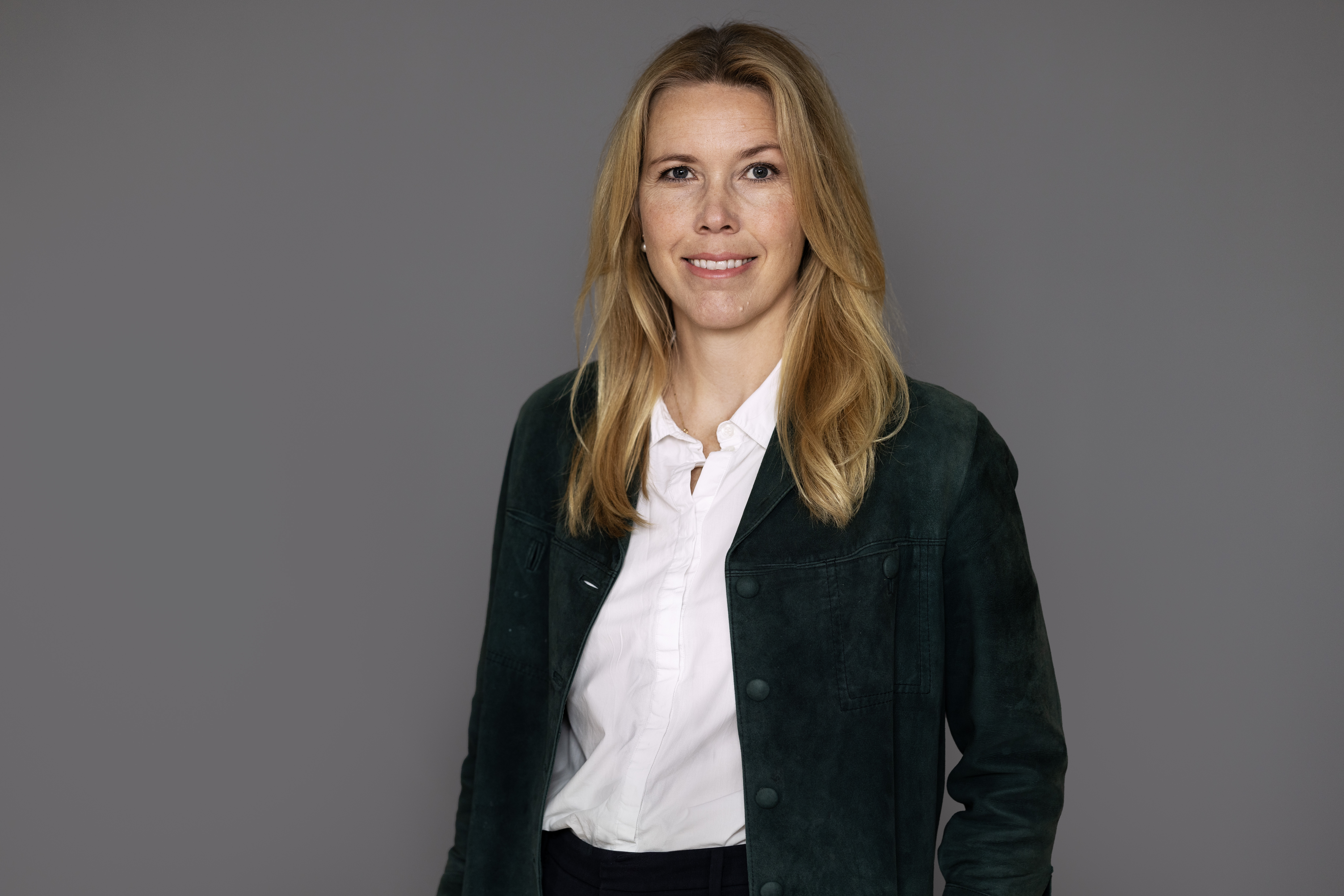 Woman wearing a black jacket and a white blouse.
